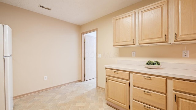 kitchen with white fridge and light brown cabinets