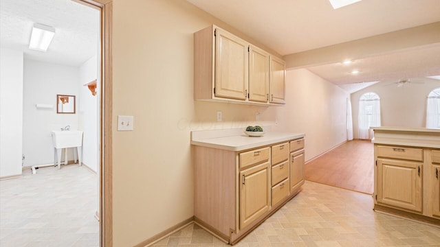 kitchen with light brown cabinetry, ceiling fan, and vaulted ceiling