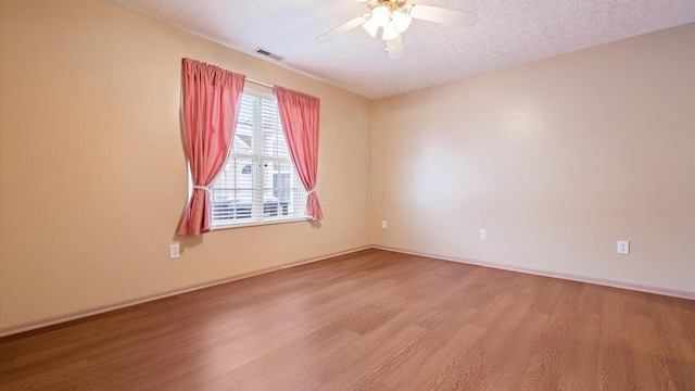 unfurnished room with ceiling fan, a textured ceiling, and light wood-type flooring