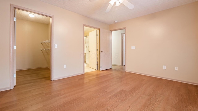 unfurnished bedroom with a spacious closet, ceiling fan, a closet, and light hardwood / wood-style flooring