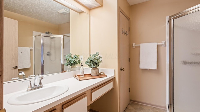 bathroom with a textured ceiling, walk in shower, and vanity