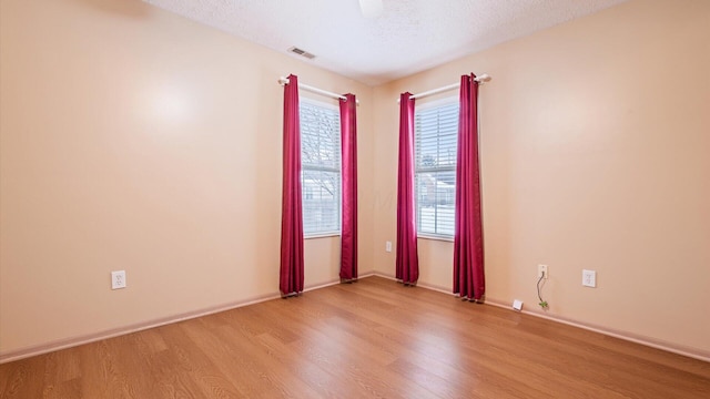 empty room featuring a textured ceiling and light hardwood / wood-style floors