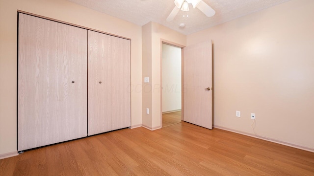 unfurnished bedroom featuring a textured ceiling, ceiling fan, a closet, and light hardwood / wood-style flooring