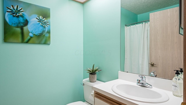 bathroom featuring toilet, vanity, a shower with shower curtain, and a textured ceiling