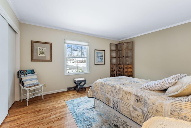 bedroom with a closet, ornamental molding, and light hardwood / wood-style flooring