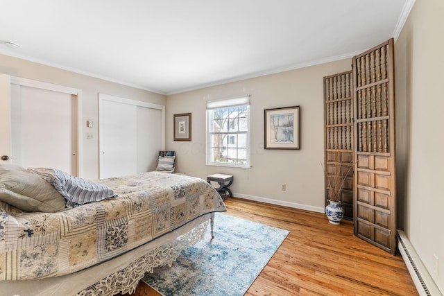 bedroom featuring baseboard heating, a closet, ornamental molding, and wood-type flooring