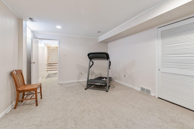 exercise room with light colored carpet and wooden walls