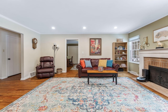 living room with wood-type flooring, a fireplace, and ornamental molding