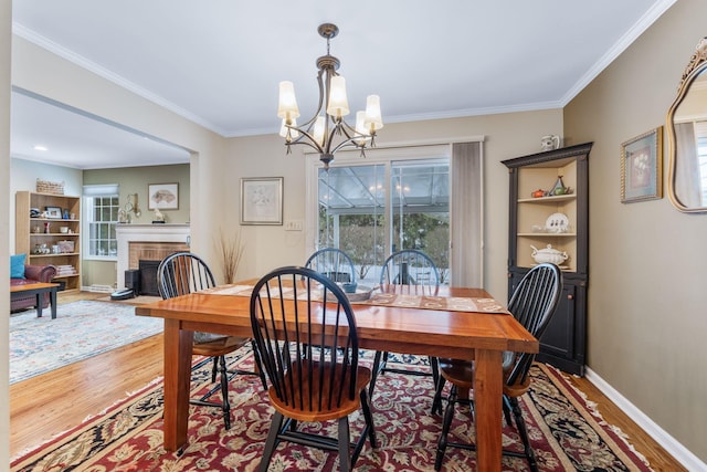 dining space with a brick fireplace, plenty of natural light, hardwood / wood-style flooring, and an inviting chandelier