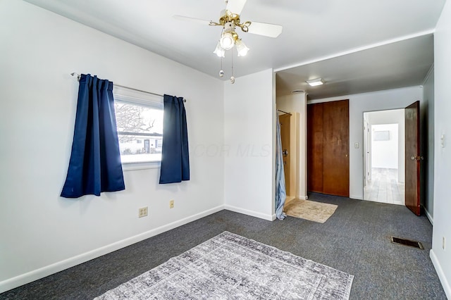 empty room featuring dark colored carpet and ceiling fan