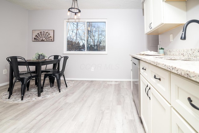 dining room featuring sink, an inviting chandelier, a textured ceiling, and light hardwood / wood-style flooring