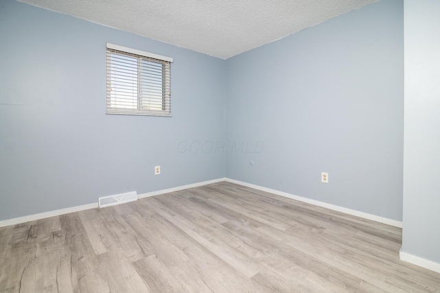 empty room featuring a textured ceiling and light hardwood / wood-style flooring