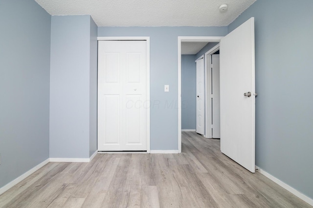 unfurnished bedroom with a textured ceiling, a closet, and light wood-type flooring