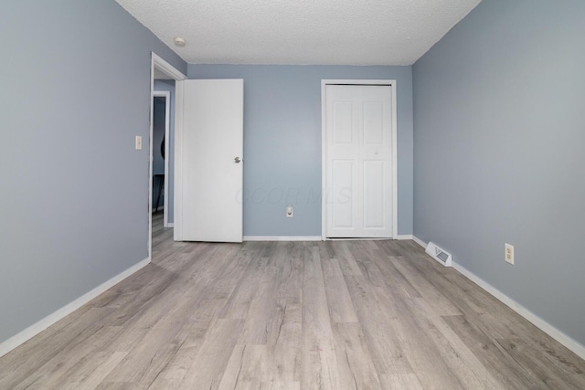 unfurnished bedroom with a textured ceiling, light hardwood / wood-style flooring, and a closet