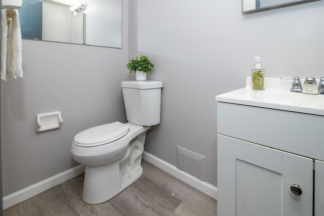 bathroom featuring toilet, hardwood / wood-style flooring, and vanity