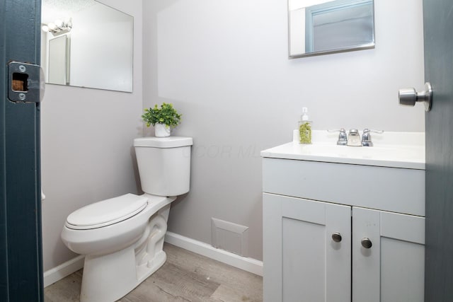 bathroom with toilet, vanity, and hardwood / wood-style floors