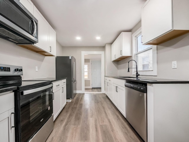 kitchen with white cabinetry, sink, light hardwood / wood-style floors, and appliances with stainless steel finishes