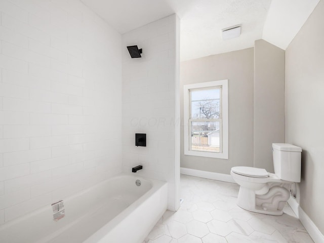 bathroom featuring tiled shower / bath, tile patterned floors, toilet, and vaulted ceiling