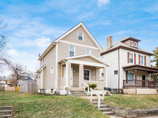 view of front of home with a storage shed, a front lawn, and covered porch