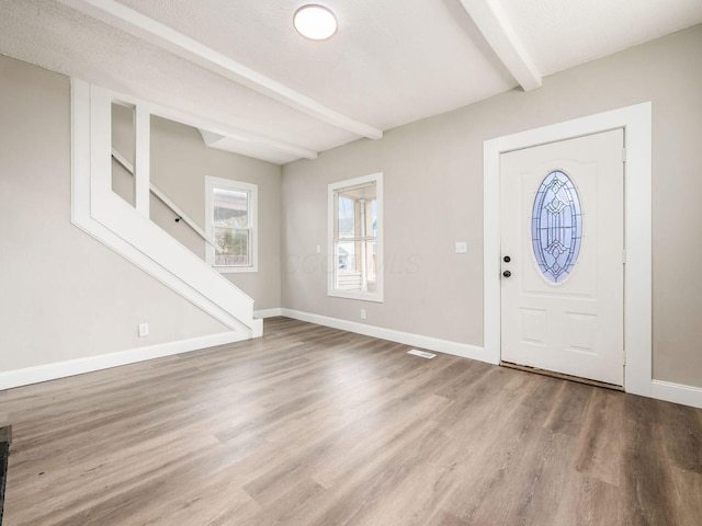 entrance foyer with beamed ceiling, hardwood / wood-style flooring, and a textured ceiling