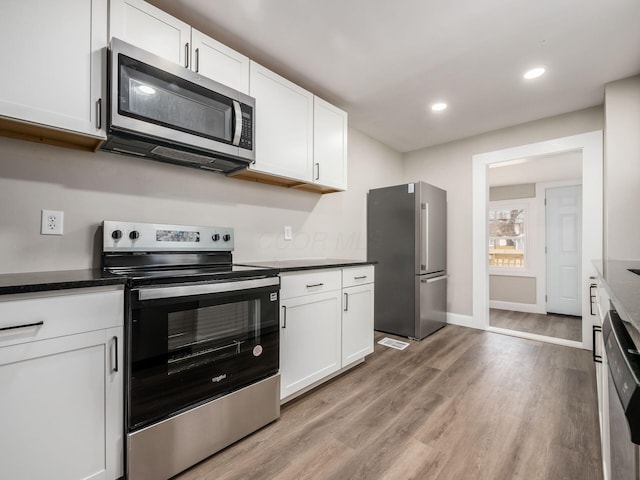 kitchen with appliances with stainless steel finishes, light hardwood / wood-style floors, and white cabinets