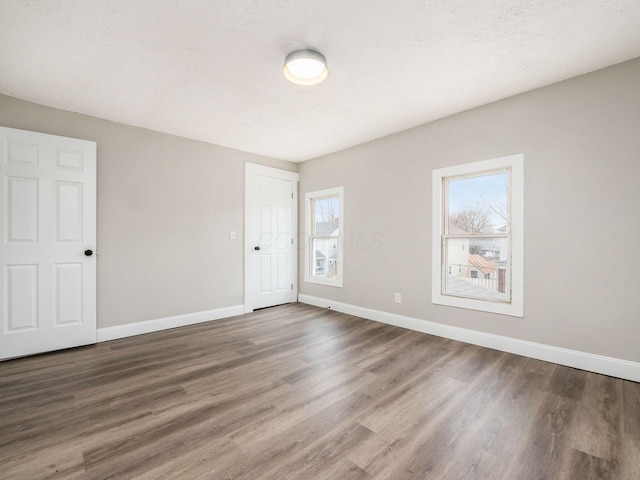 empty room with dark wood-type flooring and a textured ceiling