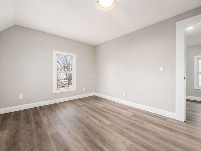 unfurnished room with hardwood / wood-style flooring, lofted ceiling, and plenty of natural light