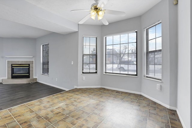 unfurnished living room featuring ceiling fan and a fireplace