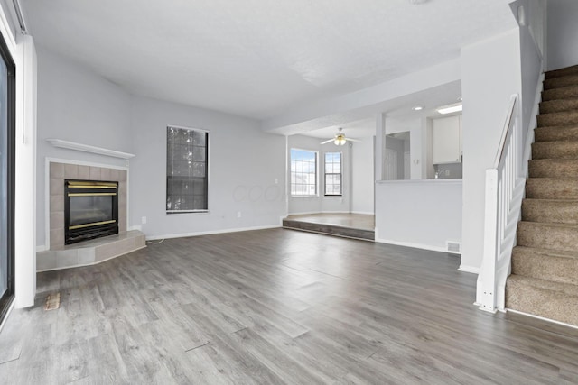 unfurnished living room featuring ceiling fan, wood-type flooring, and a fireplace