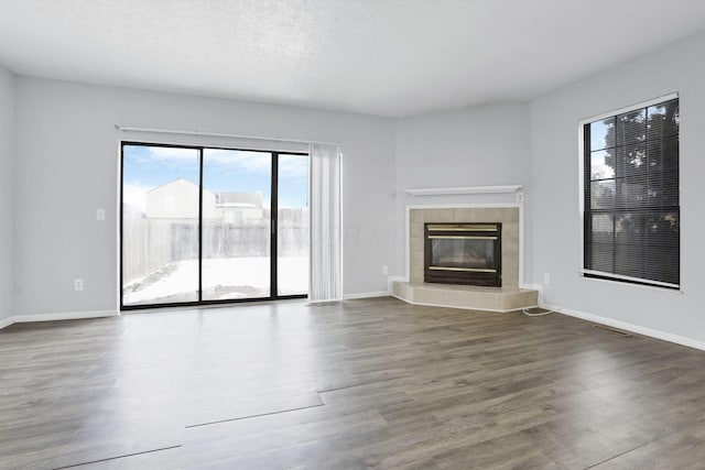 unfurnished living room with a tiled fireplace, dark hardwood / wood-style floors, and a textured ceiling