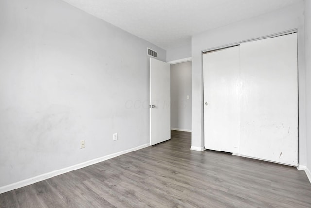 unfurnished bedroom with a closet and dark hardwood / wood-style floors