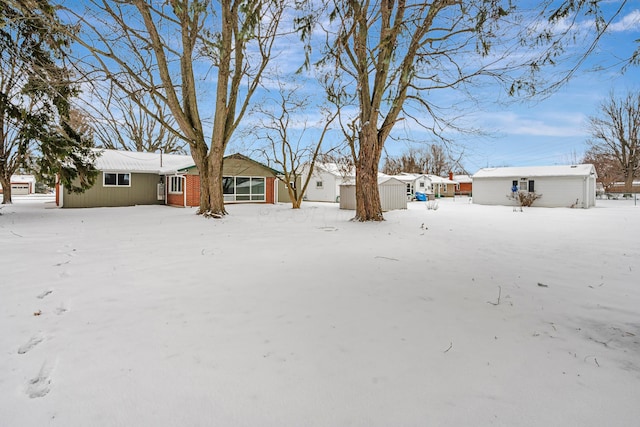 snowy yard featuring a storage unit