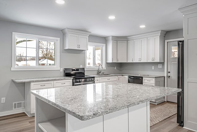 kitchen featuring a kitchen island, white cabinetry, sink, light hardwood / wood-style flooring, and stainless steel electric range