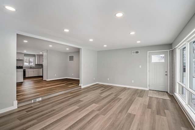 unfurnished living room featuring sink and light wood-type flooring