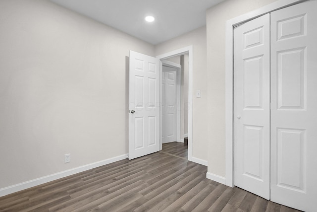 unfurnished bedroom with dark hardwood / wood-style flooring and a closet