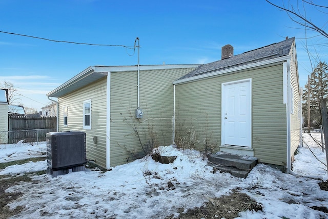 snow covered rear of property with central AC unit