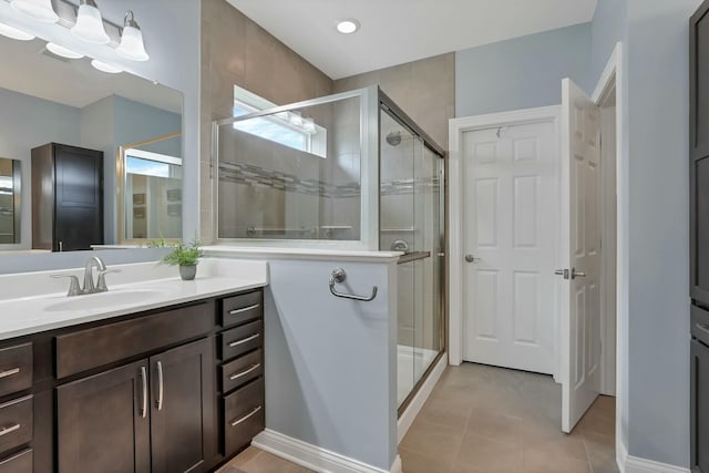 bathroom with tile patterned flooring, vanity, and walk in shower