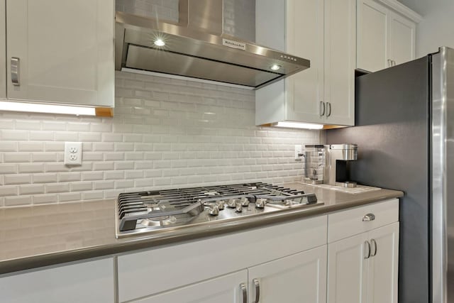 kitchen with tasteful backsplash, stainless steel appliances, white cabinets, and wall chimney exhaust hood