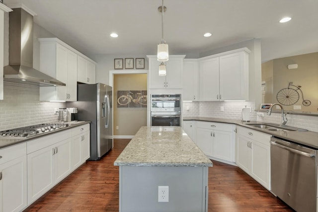 kitchen with wall chimney exhaust hood, sink, a center island, appliances with stainless steel finishes, and white cabinets