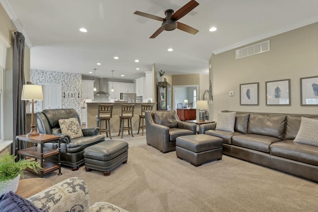 living room with crown molding, light colored carpet, and ceiling fan