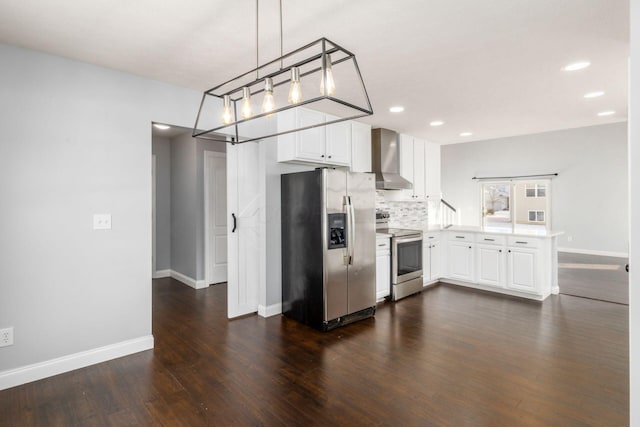 kitchen featuring appliances with stainless steel finishes, pendant lighting, white cabinetry, decorative backsplash, and wall chimney exhaust hood