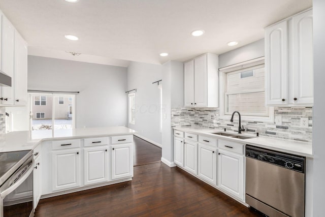 kitchen with appliances with stainless steel finishes, white cabinetry, sink, kitchen peninsula, and dark wood-type flooring