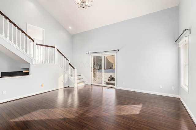 unfurnished living room with an inviting chandelier, dark wood-type flooring, and high vaulted ceiling