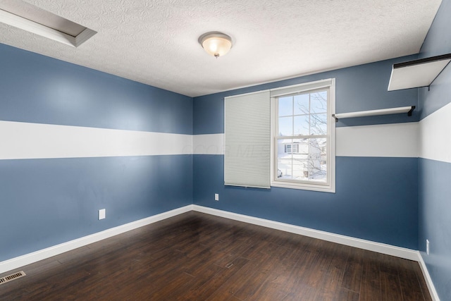 spare room with dark hardwood / wood-style floors and a textured ceiling