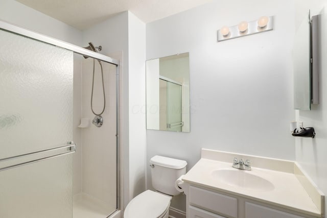 bathroom featuring vanity, a shower with door, and toilet