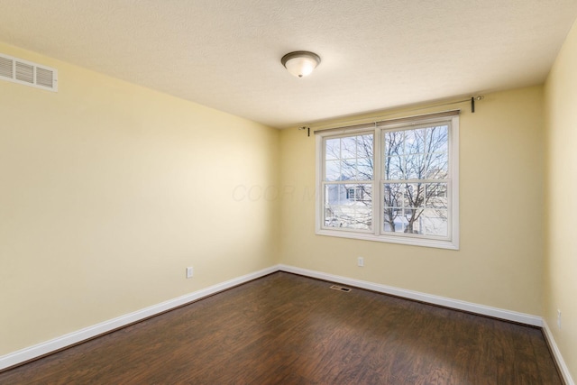 empty room with dark hardwood / wood-style floors and a textured ceiling