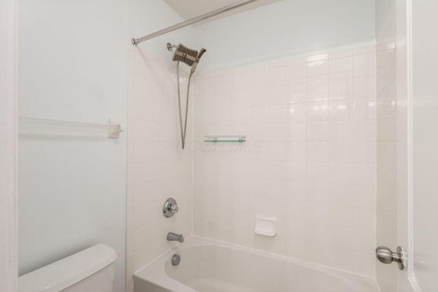 bathroom with tiled shower / bath combo and toilet