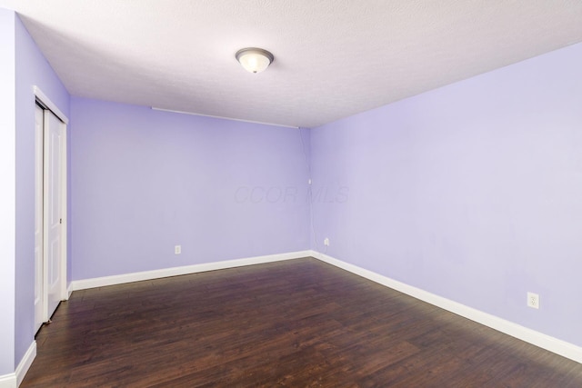 empty room featuring dark hardwood / wood-style flooring and a textured ceiling