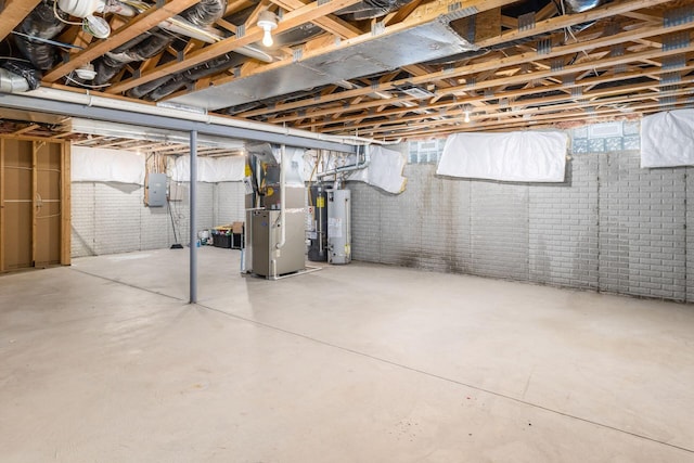 basement with heating unit, gas water heater, electric panel, and brick wall