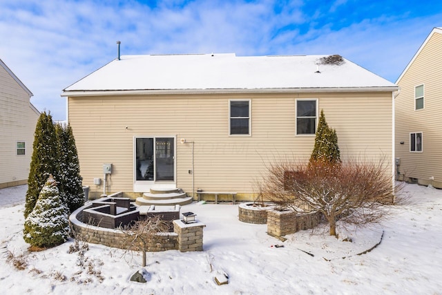 snow covered back of property featuring an outdoor fire pit